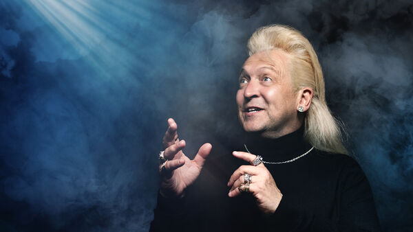 Clinton Baptiste in a black turtleneck and gold chain looking up to a light