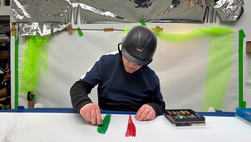 A man in a helmet draws with coloured chalks