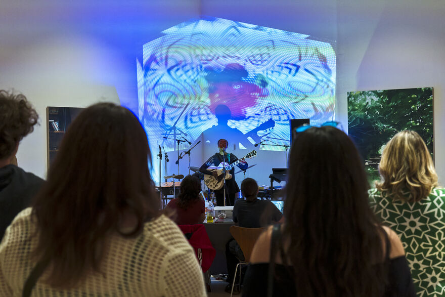 Performer playing guitar with people watching on 