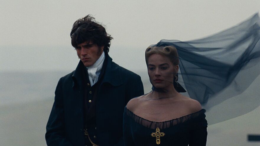 Margot Robbie and Jacob Elordi as Cathy and Heathcliff. They stand together dressed in all black. 