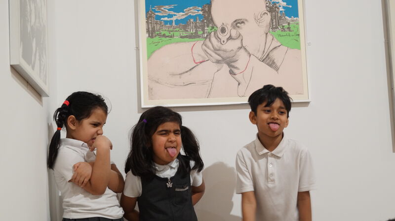 Three children in a gallery sticking out their tongues 