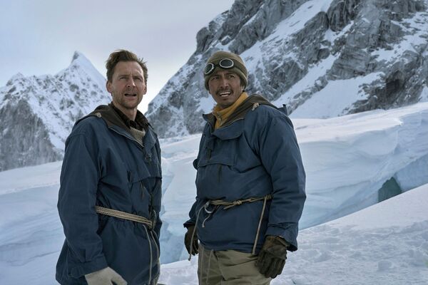 Tom Hiddleston as Edmund Hillary and Genden Phuntsok as Tenzing Norgay standing on a snowy mountainside. 