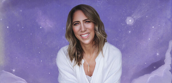 Woman smiling and sitting in front of a purple background