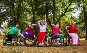 5 people in wheelchairs with green trees behind them