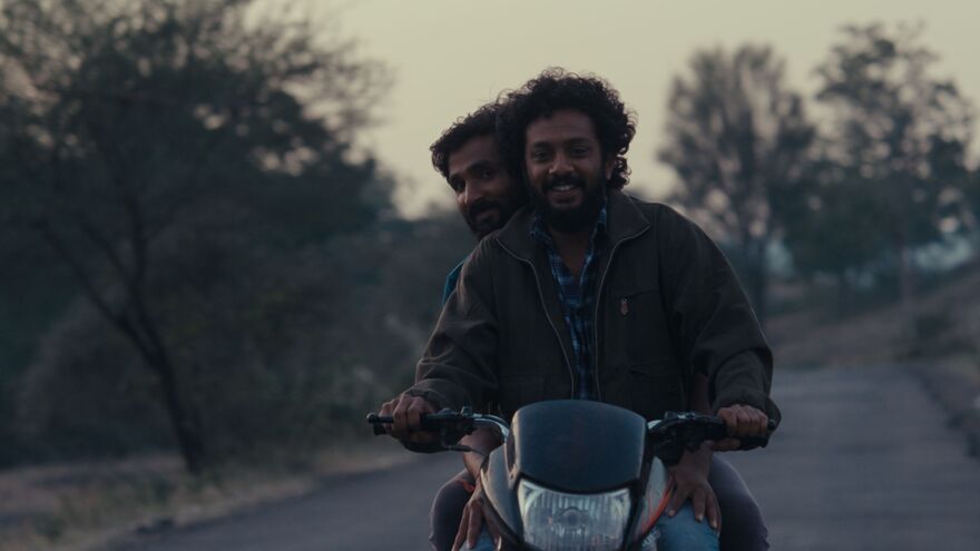 Two men ride a motorcycle together. 