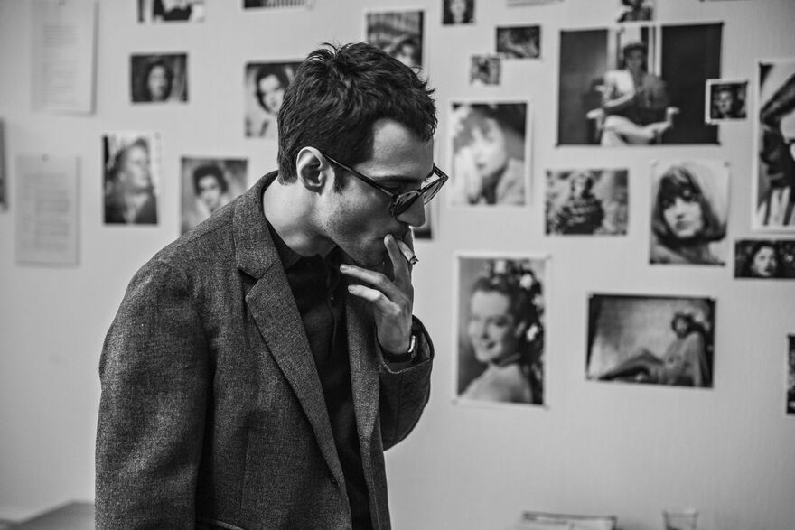 A black and white image of Guillaume Marbeck as Jean-Luc Godard smoking a cigarette. 
