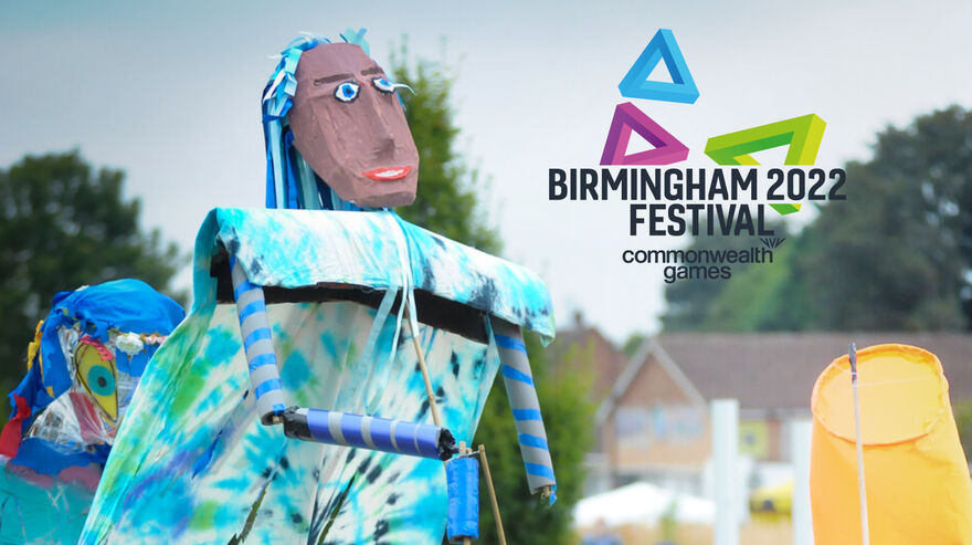 Large parade puppets outdoors with Birmingham 2022 festival logo.