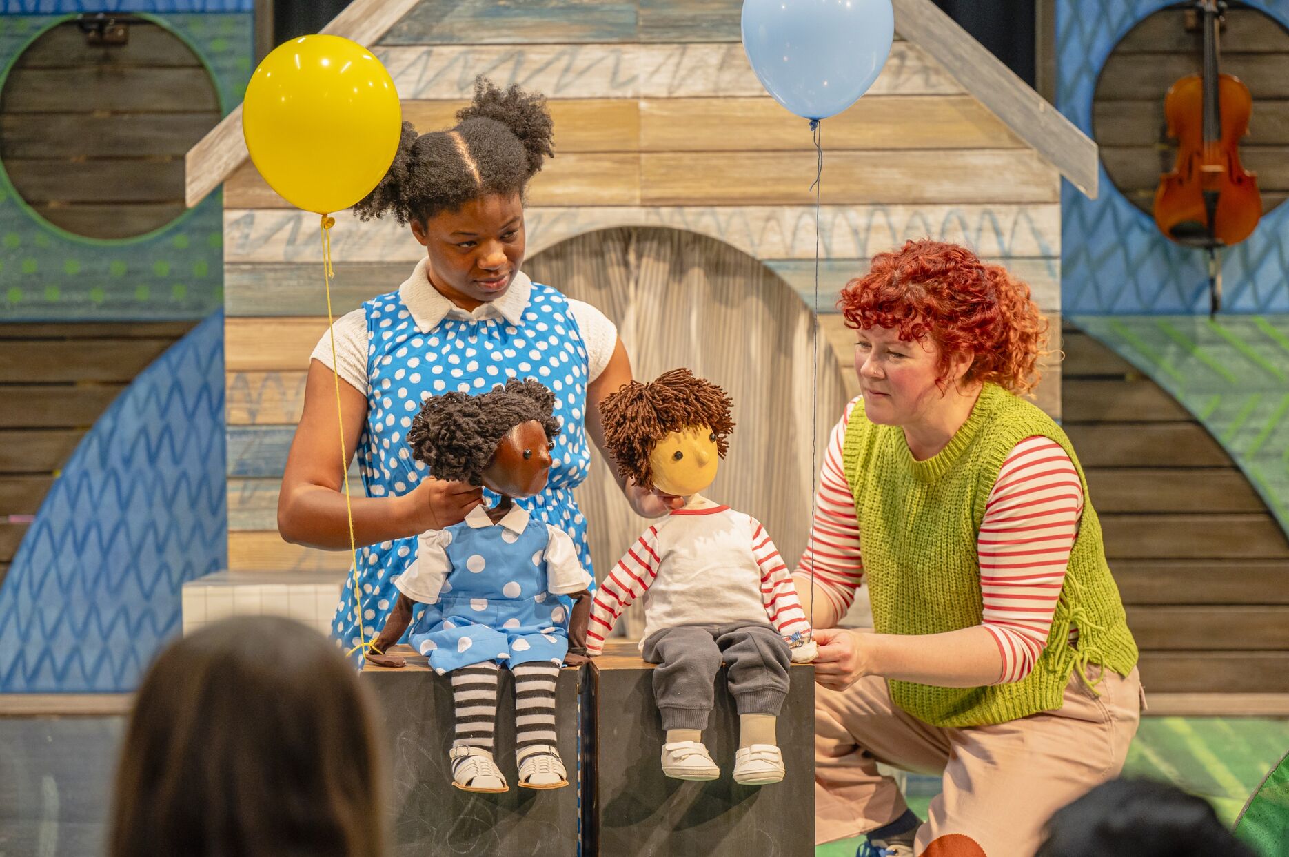 Two people on stage with two puppets and two balloons