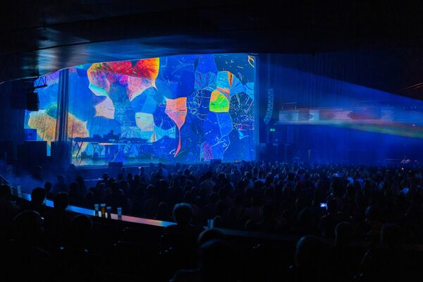 Large blue projection on stage with a mixture of leaves