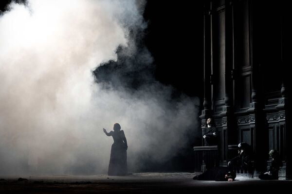 A woman stands silhouetted in a cloud of smoke.  