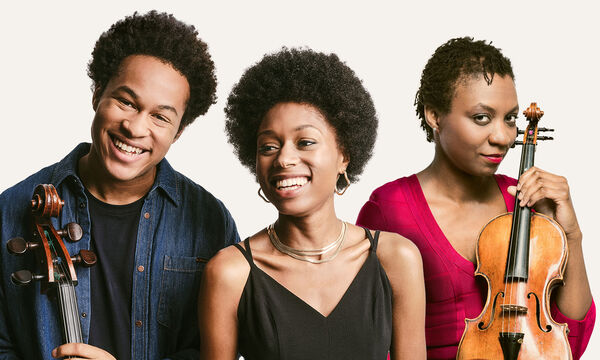 Three performers smiling and holding their instruments
