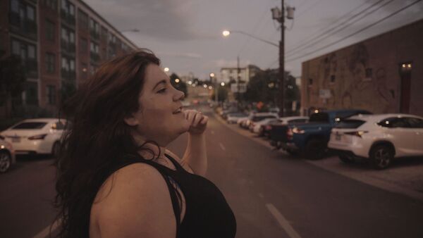 A young woman walks across a road. 