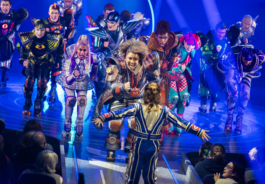 A group of brightly dressed people on roller skates. 