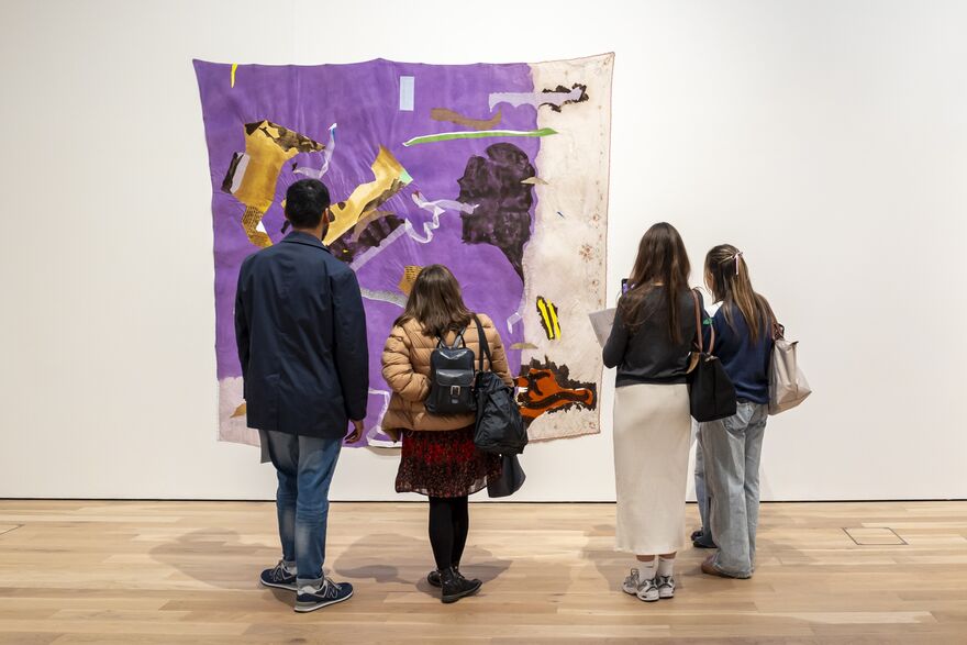 4 people looking at a colourful artwork on the wall