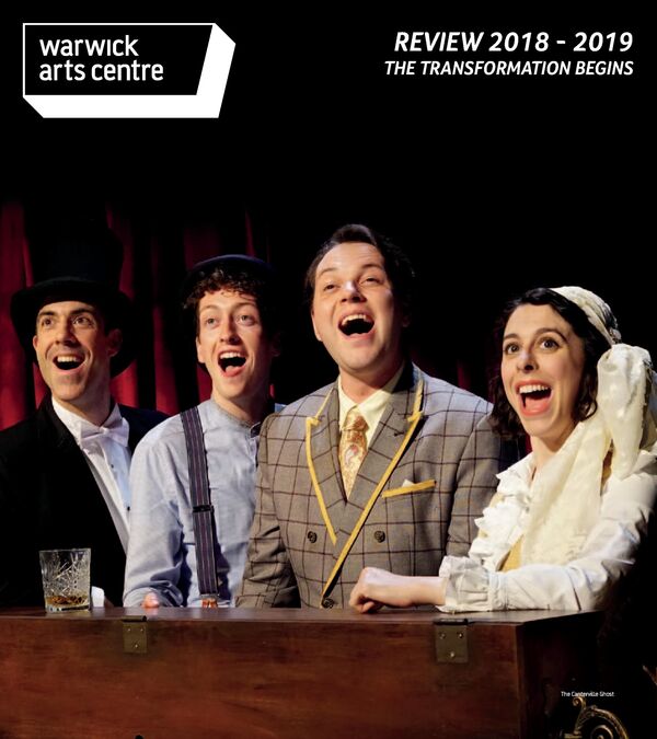 Four performers on stage in costume singing around a piano
