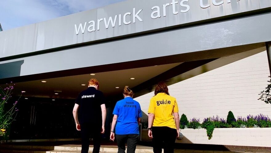 A group of apprentices and volunteers walking up the steps to the Warwick Arts Centre Entrance
