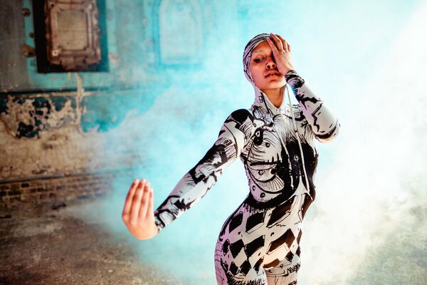 Woman covering an eye with one hand with the other outstretched pointing up 