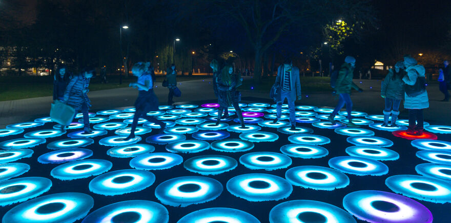 Image of Art Installation by Craig Holmes - It shows people standing on illuminated circles - titled: The Pool - 2014