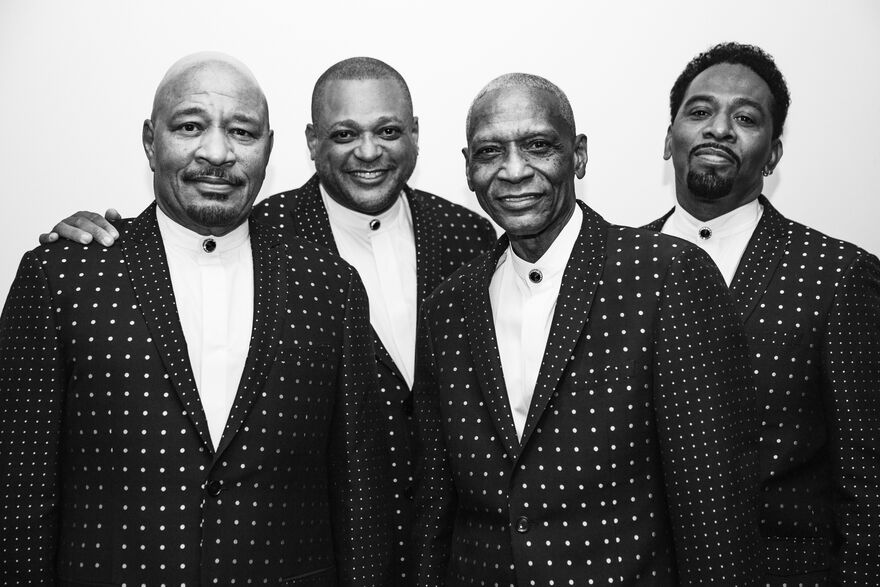 The Stylistics stood in spotty suits, image is in black and white