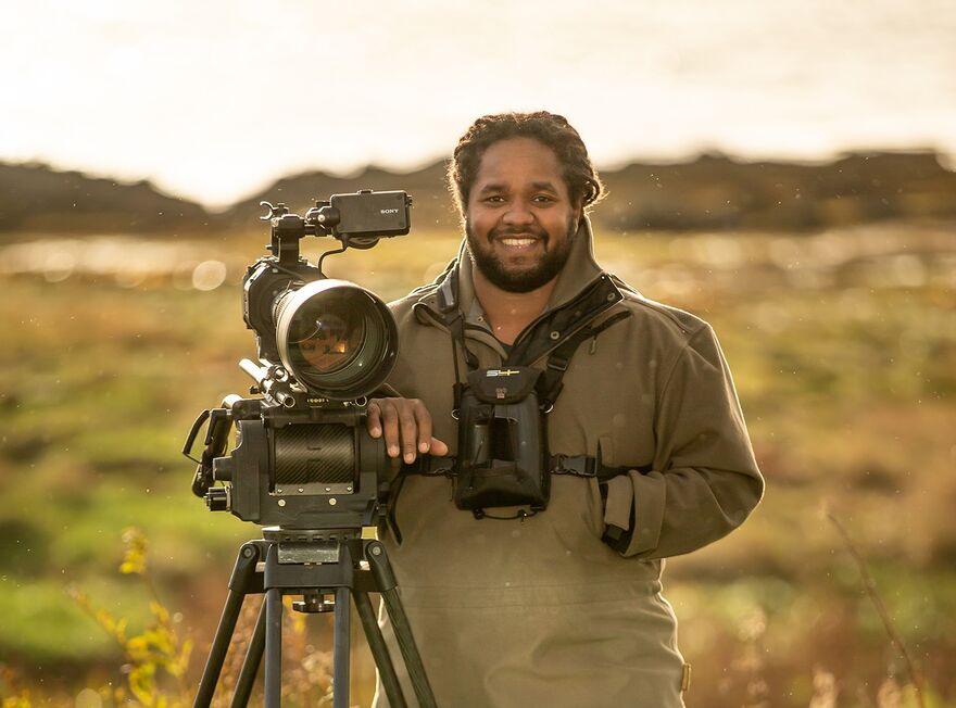 Hamza Yassin stood in a field next to a large camera