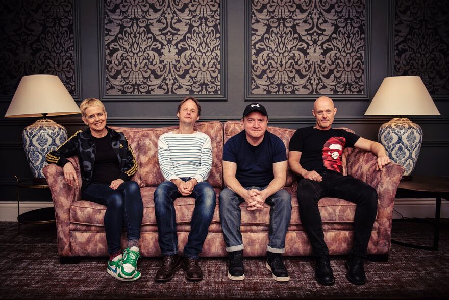 Four people sat on a salmon coloured sofa