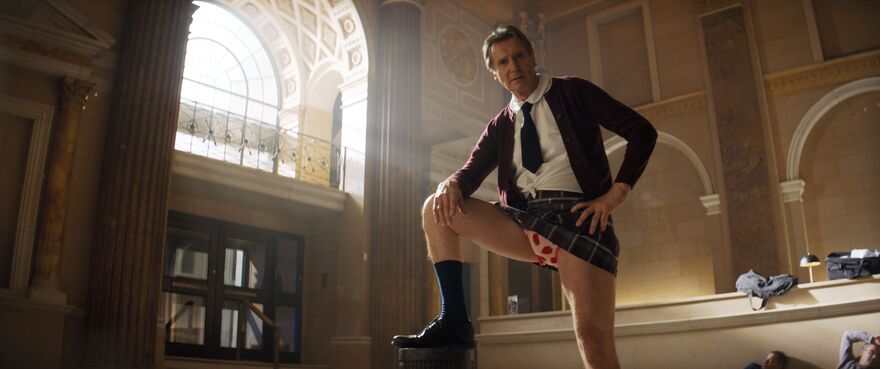 An older man wears a school uniform with a short chequered skirt revealing strawberry patterned underwear.