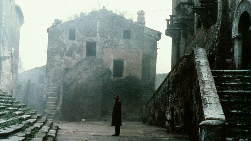 A man stands in an empty, grey village. 