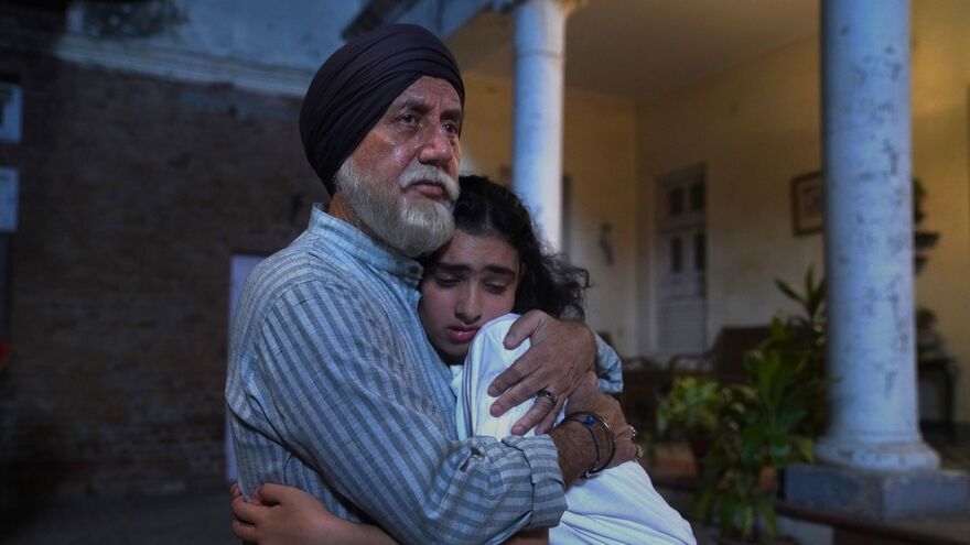 An older man hugs a young girl tightly. 