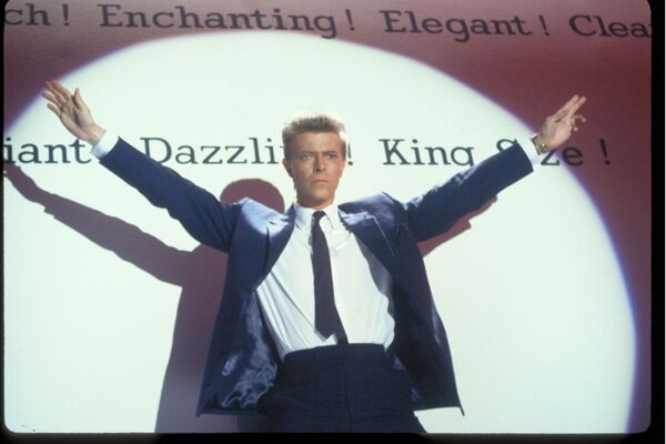 David Bowie in a spotlight with both arms up