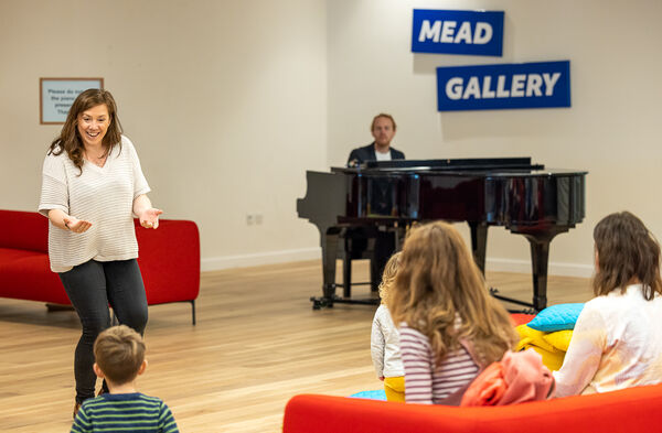 Woman leading a singing session in Warwick Arts Centre's foyer space