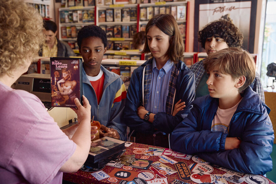 A group of four boys at the counter of a video store. 