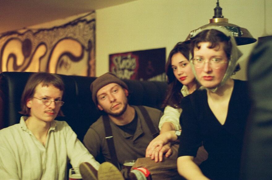 The four members of Goblin Band sat in a booth, looking at the camera 