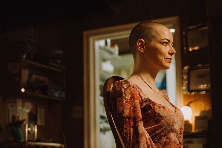 A woman with a shaved head sits at a table. 
