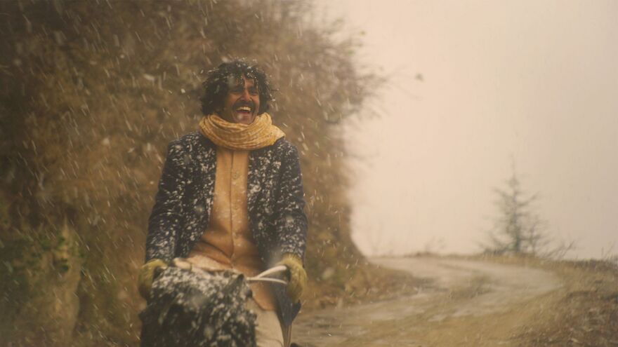 A man rides a bike in the snow smiling widely. 