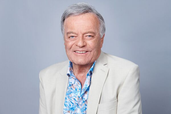 Tony Blackburn smiling in a white suit and blue shirt