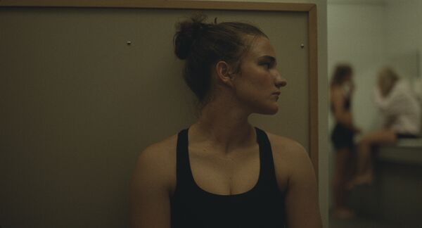 A young woman sits behind a wall, hiding from view. 