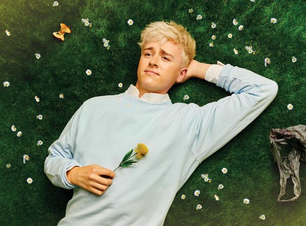 Daniel Foxx laying on the grass surrounded by small white flowers