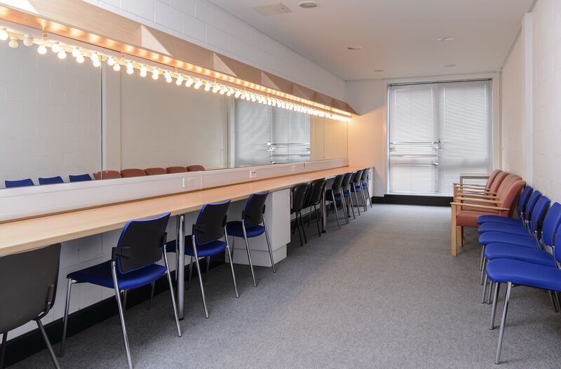 Long and thin dressing room with lights around the mirrors turned on