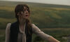 A woman stands in a field looking concerned