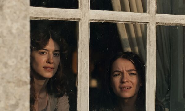 Two young women look out of a window. Two young women look out of a window.