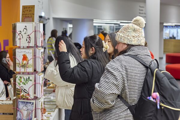 Group of people looking at prints on a stand