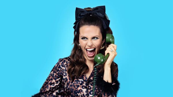 Ellie Taylor with a big black bow in her hair and holding a big green phone to her ear
