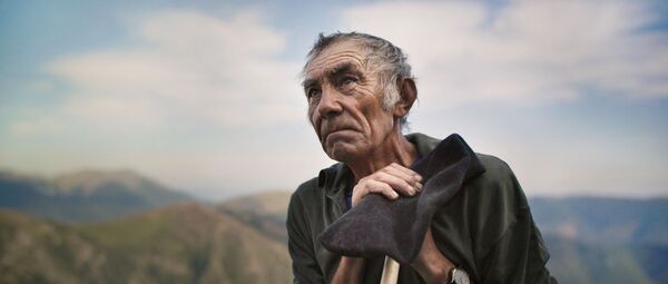 An old shepherd with out of focus mountains in the background. 