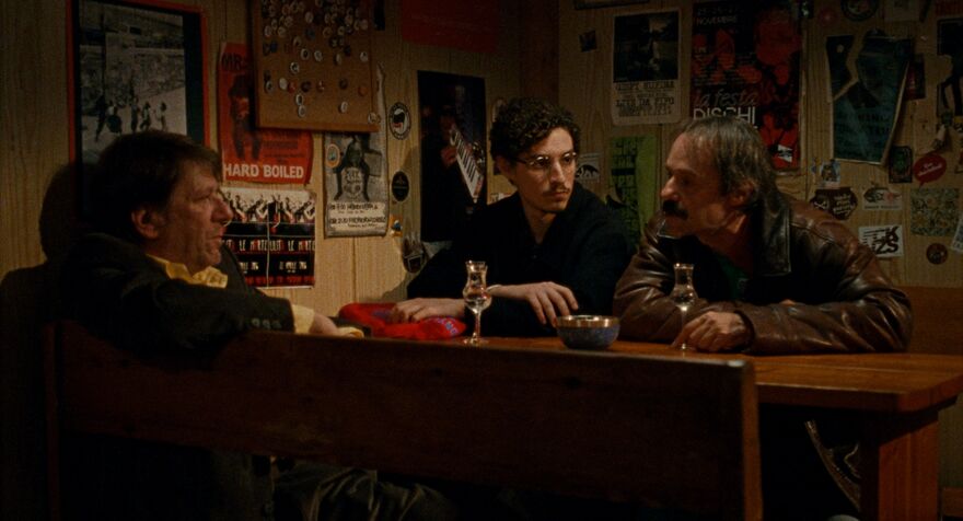 Three men sit together drinking at a bar. 