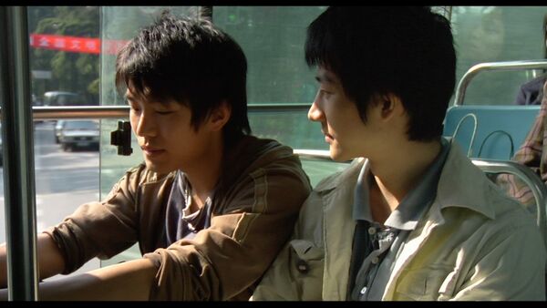 Two young men sit together on a bus. 