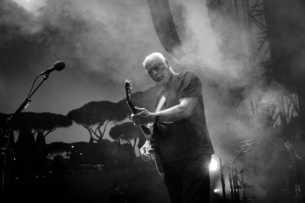A black and white photo of David Gilmour playing the guitar. 