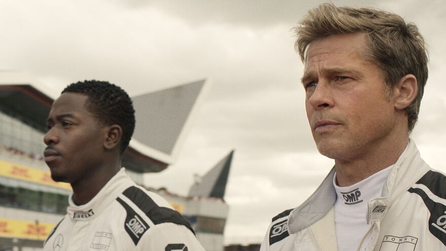 Two F1 drivers stand together looking forward.