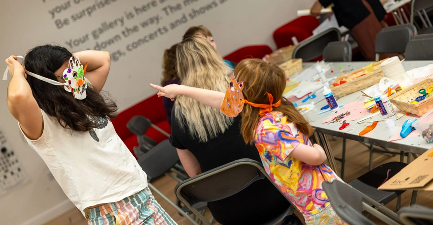 Young girl wearing a mask points at someone else wearing a mask