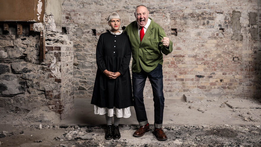 Keith Brymer Jones and Marj Hogarth stood in front of a broken brick wall