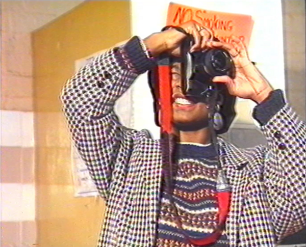 A woman squints looking through a camera. 